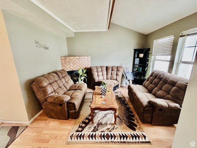 4946 W Pawnee Dr, West Jordan, UT 84081 - living area featuring wood finished floors, vaulted ceiling, a textured ceiling, crown molding, and a glass covered fireplace