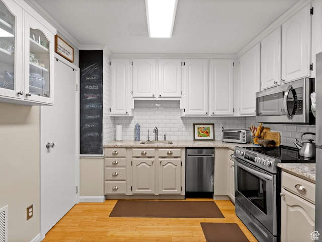 123 E 2nd Ave Unit 502, Salt Lake City, UT 84103 - kitchen featuring stainless steel appliances, tasteful backsplash, light wood-style flooring, and white cabinets