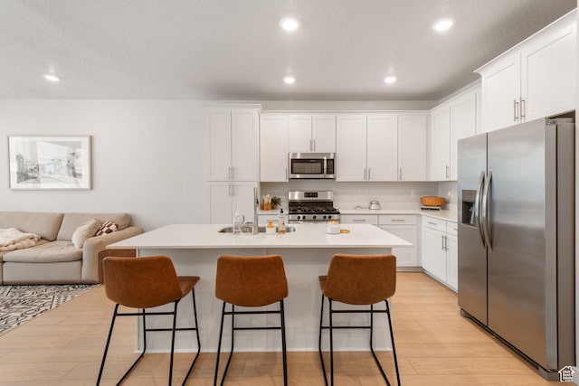 938 W Terracotta Dr, Saratoga Springs, UT 84045 - kitchen with stainless steel appliances, light wood-type flooring, a breakfast bar area, white cabinets, and recessed lighting