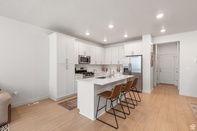 938 W Terracotta Dr, Saratoga Springs, UT 84045 - kitchen with stainless steel appliances, light wood finished floors, a breakfast bar area, recessed lighting, and white cabinets