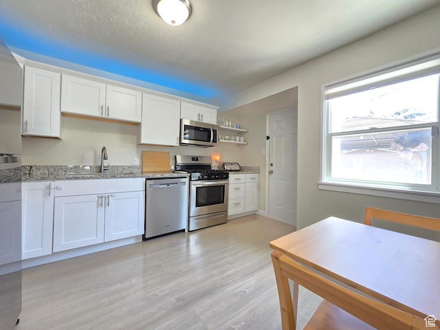 4321 W 5655 S, Salt Lake City, UT 84118 - kitchen with appliances with stainless steel finishes, light stone counters, white cabinetry, open shelves, and light wood-type flooring