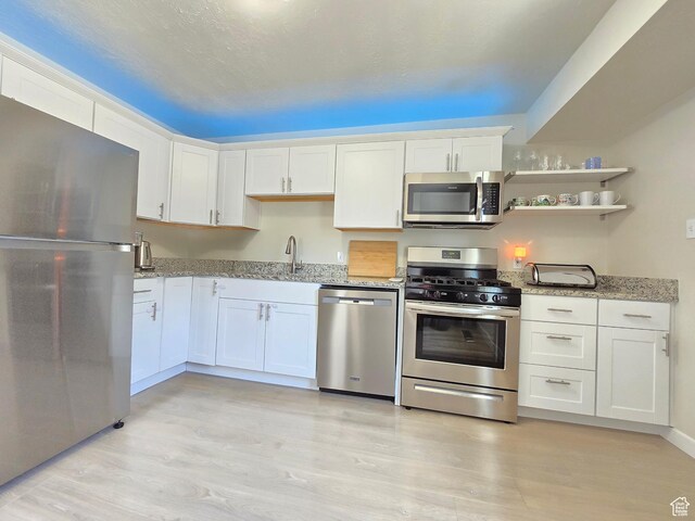 4321 W 5655 S, Salt Lake City, UT 84118 - kitchen with stainless steel appliances, light wood-style floors, white cabinetry, light stone counters, and open shelves