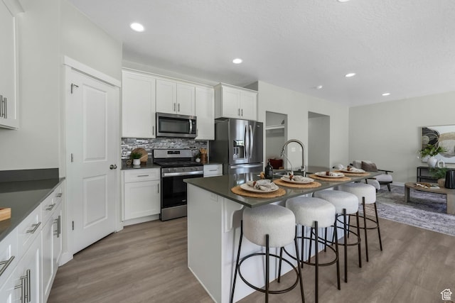 1666 W Rockaway Ln, West Jordan, UT 84084 - kitchen featuring stainless steel appliances, dark countertops, a kitchen bar, tasteful backsplash, and recessed lighting