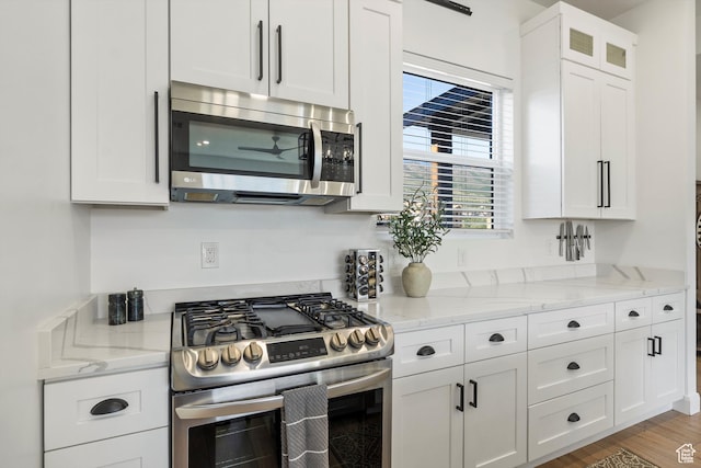 3547 N Creekside Way, Eden, UT 84310 - kitchen featuring appliances with stainless steel finishes, white cabinetry, light stone countertops, and wood finished floors