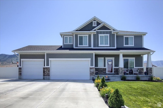 342 E Chiswick Ct, Stansbury Park, UT 84074 - craftsman house featuring a porch, driveway, stone siding, a mountain view, and an attached garage