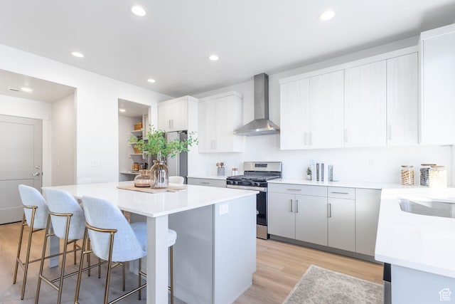2727 N 2775 W Unit 122, Plain City, UT 84404 - kitchen with wall chimney range hood, appliances with stainless steel finishes, a center island, a breakfast bar, and light wood-style floors
