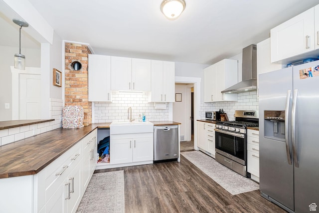 141 W 400 N, Logan, UT 84321 - kitchen featuring appliances with stainless steel finishes, wall chimney exhaust hood, wood counters, and decorative backsplash