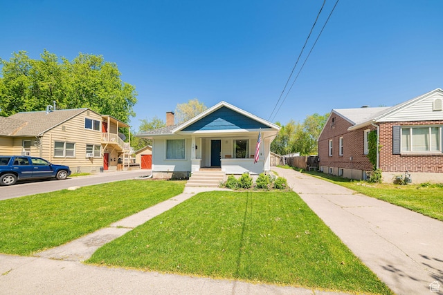 141 W 400 N, Logan, UT 84321 - bungalow featuring covered porch, a chimney, a front lawn, and concrete driveway