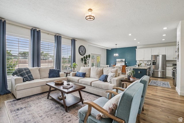 2577 W Garden Creek Way Unit 106, West Jordan, UT 84088 - living area with light wood-type flooring, a textured ceiling, plenty of natural light, and recessed lighting