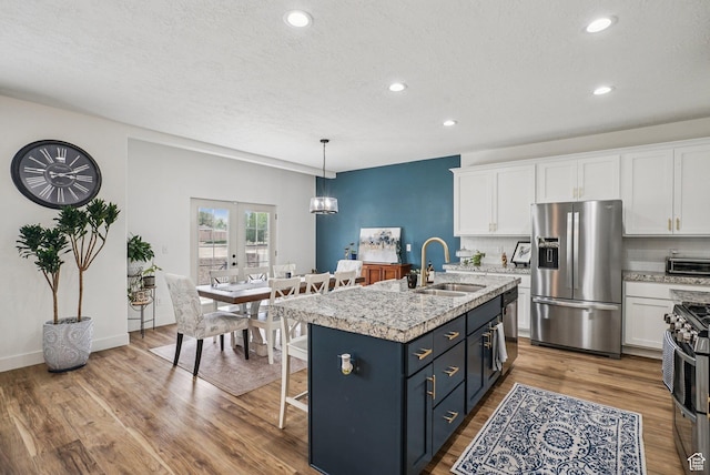 2577 W Garden Creek Way Unit 106, West Jordan, UT 84088 - kitchen with appliances with stainless steel finishes, white cabinets, recessed lighting, wood finished floors, and an island with sink