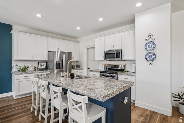 2577 W Garden Creek Way Unit 106, West Jordan, UT 84088 - kitchen featuring stainless steel appliances, a center island with sink, decorative backsplash, dark wood-type flooring, and recessed lighting