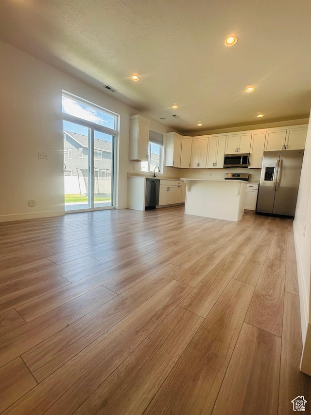 764 S 290 W, American Fork, UT 84003 - kitchen featuring appliances with stainless steel finishes, light wood-type flooring, white cabinetry, open floor plan, and a kitchen island