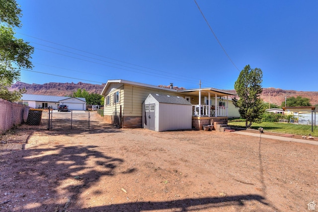 1281 Holyoak Ln E, Moab, UT 84532 - view of front of house featuring a mountain view, a gate, a shed, a detached garage, and covered porch