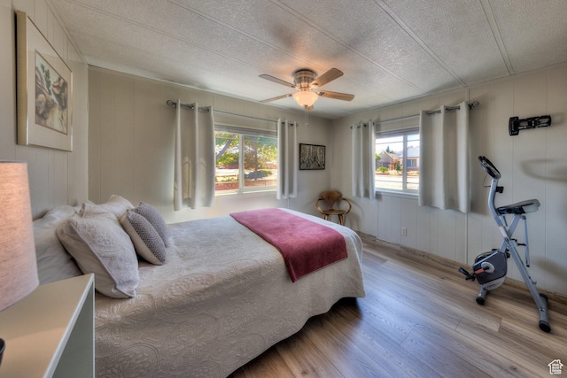 1281 Holyoak Ln E, Moab, UT 84532 - bedroom with light wood-type flooring, multiple windows, a textured ceiling, ceiling fan, and a decorative wall