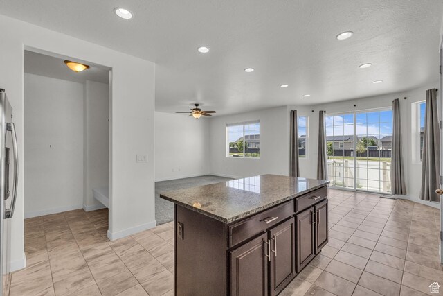 773 W Mulberry St, Stansbury Park, UT 84074 - kitchen with recessed lighting, healthy amount of natural light, ceiling fan, dark brown cabinetry, and light stone countertops