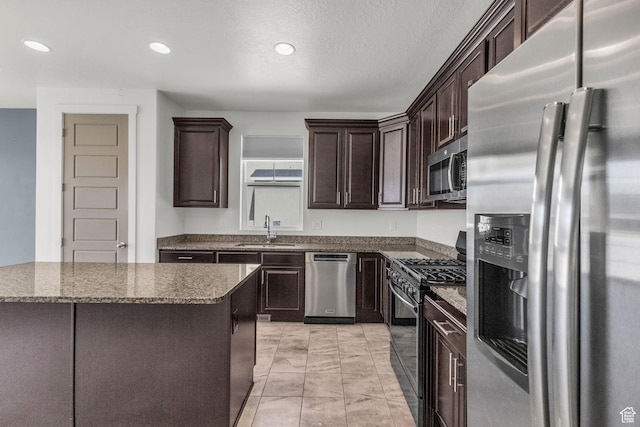 773 W Mulberry St, Stansbury Park, UT 84074 - kitchen featuring appliances with stainless steel finishes, dark brown cabinetry, dark stone counters, light marble finish flooring, and recessed lighting