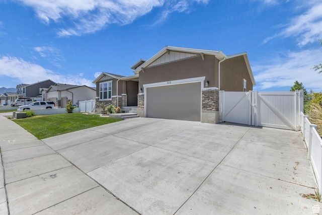 773 W Mulberry St, Stansbury Park, UT 84074 - view of front facade with a gate, a garage, stone siding, concrete driveway, and stucco siding