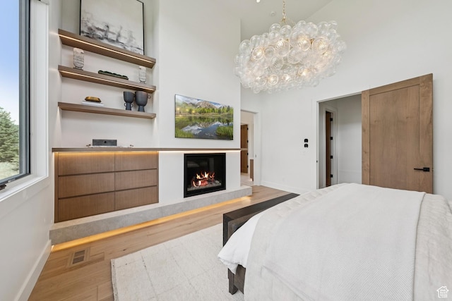 1404 W Ursa Way, Heber City, UT 84032 - bedroom with wood finished floors, a glass covered fireplace, a chandelier, and a high ceiling