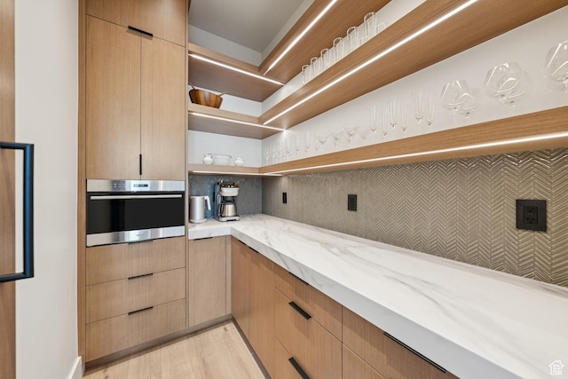 1404 W Ursa Way, Heber City, UT 84032 - kitchen with stainless steel oven, open shelves, light stone counters, light wood-style floors, and light brown cabinetry