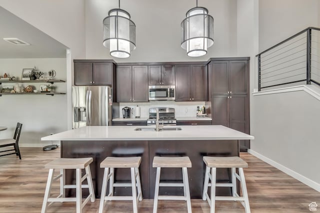 10363 S Silver Mine Rd, South Jordan, UT 84009 - kitchen featuring appliances with stainless steel finishes, dark brown cabinetry, a towering ceiling, and a breakfast bar area