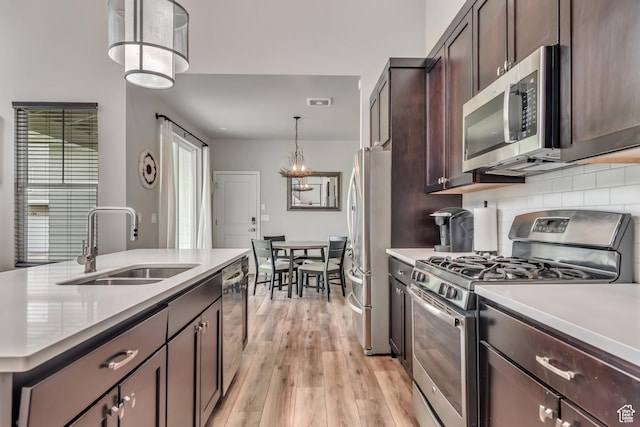 10363 S Silver Mine Rd, South Jordan, UT 84009 - kitchen with stainless steel appliances, dark brown cabinets, light countertops, light wood-type flooring, and backsplash