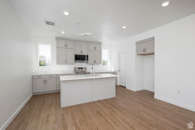 924 W Coalburn Way Unit 8-26, Murray, UT 84123 - kitchen featuring appliances with stainless steel finishes, gray cabinets, a center island with sink, light wood finished floors, and light countertops