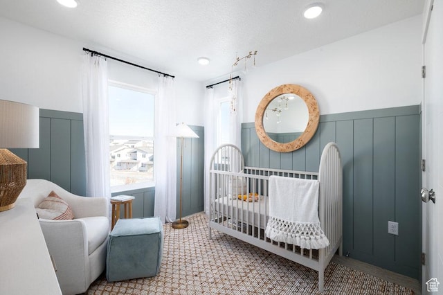 924 W Coalburn Way Unit 8-26, Murray, UT 84123 - bedroom featuring a wainscoted wall, a nursery area, a textured ceiling, and a decorative wall