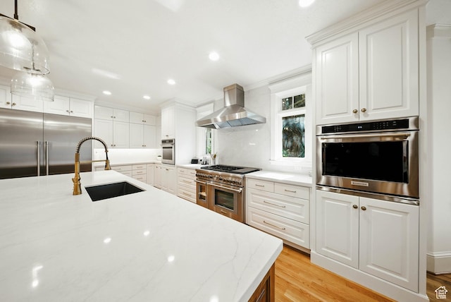 1734 E Spring Ln, Holladay, UT 84117 - kitchen with high end appliances, wall chimney exhaust hood, light wood finished floors, recessed lighting, and white cabinetry
