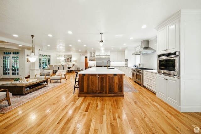 1734 E Spring Ln, Holladay, UT 84117 - kitchen with wall chimney range hood, high quality appliances, open floor plan, light countertops, and light wood-type flooring