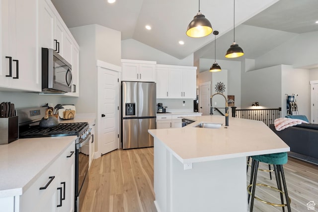507 W 2030 N, Tooele, UT 84074 - kitchen with stainless steel appliances, vaulted ceiling, light wood-style flooring, a breakfast bar area, and an island with sink