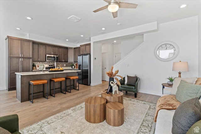 11568 S Watercourse Rd, South Jordan, UT 84009 - living room with a ceiling fan, light wood finished floors, recessed lighting, and stairs