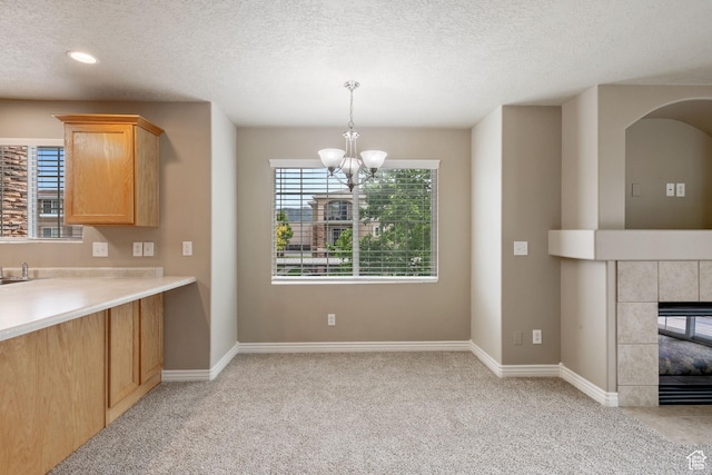 211 E Spencer Peak Way Unit H6, Draper, UT 84020 - kitchen featuring a chandelier, light carpet, light countertops, a textured ceiling, and a tile fireplace