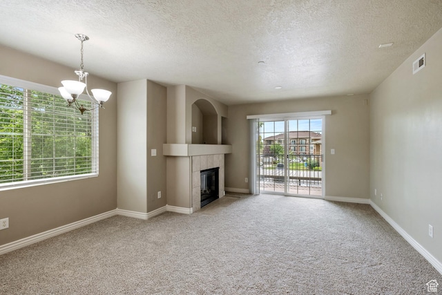 211 E Spencer Peak Way Unit H6, Draper, UT 84020 - unfurnished living room featuring a textured ceiling, a chandelier, light carpet, and a tiled fireplace
