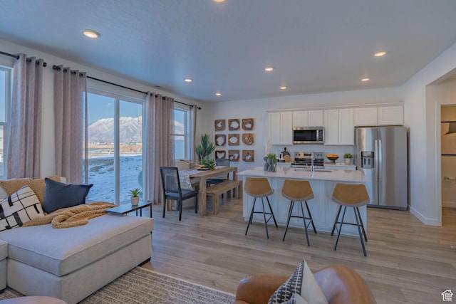 1710 N 784 W, Salem, UT 84653 - kitchen with stainless steel appliances, a kitchen island with sink, white cabinets, a breakfast bar, and light wood-style floors