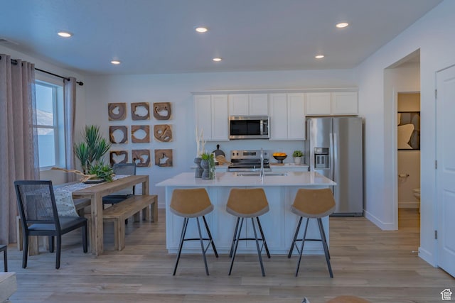 1710 N 784 W, Salem, UT 84653 - kitchen featuring appliances with stainless steel finishes, a center island with sink, light countertops, a breakfast bar area, and light wood-style flooring