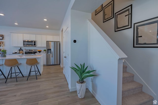 1710 N 784 W, Salem, UT 84653 - kitchen featuring stainless steel appliances, a breakfast bar, white cabinetry, light countertops, and light wood-type flooring