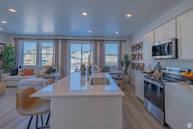1710 N 784 W, Salem, UT 84653 - kitchen with appliances with stainless steel finishes, open floor plan, light wood-style flooring, recessed lighting, and a center island with sink