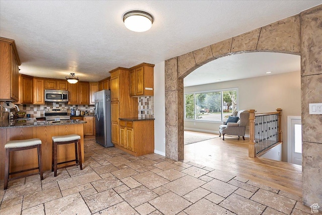 315 E 900 N, Brigham City, UT 84302 - kitchen with stainless steel appliances, arched walkways, stone tile floors, open floor plan, and brown cabinets