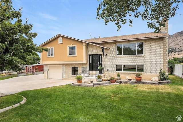 315 E 900 N, Brigham City, UT 84302 - split foyer home with concrete driveway, brick siding, an attached garage, and a front lawn
