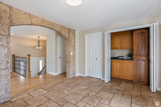 315 E 900 N, Brigham City, UT 84302 - kitchen featuring arched walkways, stone tile flooring, brown cabinetry, and dark countertops