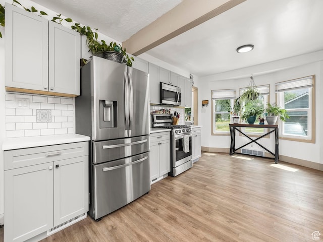 1116 S Liberty Ave, Ogden, UT 84404 - kitchen with stainless steel appliances, decorative backsplash, light countertops, light wood-type flooring, and beamed ceiling