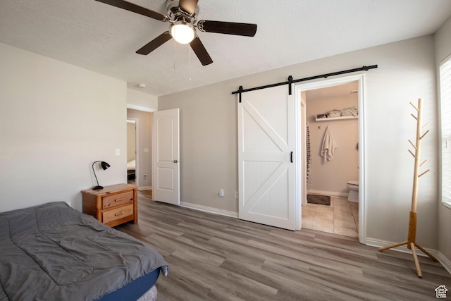 3408 S Carrick Dr W, South Salt Lake, UT 84115 - bedroom with wood finished floors, a barn door, connected bathroom, and a ceiling fan