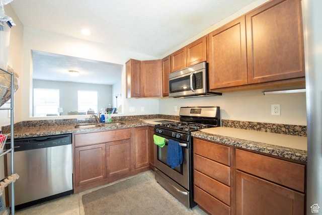 3408 S Carrick Dr W, South Salt Lake, UT 84115 - kitchen featuring appliances with stainless steel finishes, brown cabinetry, dark stone counters, and recessed lighting