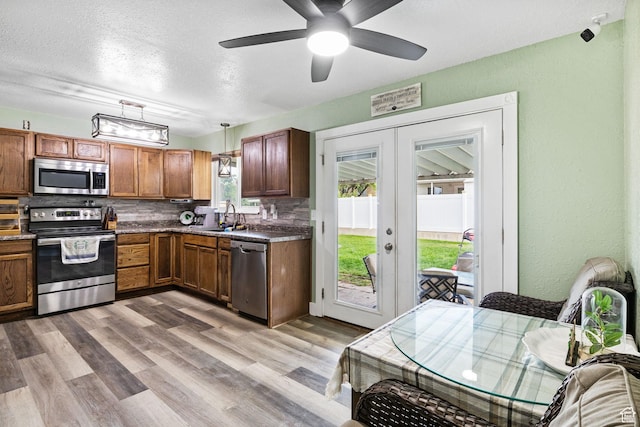 4895 W Pavant Ave, West Valley City, UT 84120 - kitchen with stainless steel appliances, french doors, decorative backsplash, dark countertops, and brown cabinetry