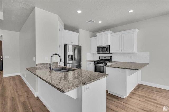 424 N Highland Pkwy, Washington, UT 84780 - kitchen featuring appliances with stainless steel finishes, a peninsula, dark stone countertops, light wood-type flooring, and recessed lighting