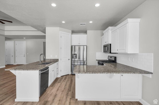 424 N Highland Pkwy, Washington, UT 84780 - kitchen featuring appliances with stainless steel finishes, a peninsula, stone countertops, light wood-style flooring, and recessed lighting
