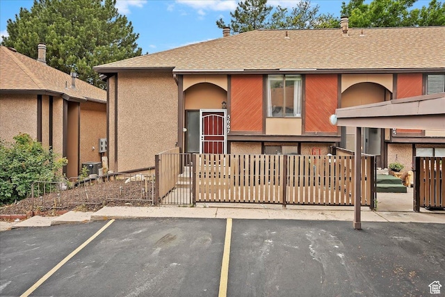 5667 S Aspen Ct E, South Ogden, UT 84403 - view of front facade featuring a fenced front yard, uncovered parking, roof with shingles, stucco siding, and a gate