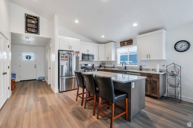 128 E 840 N, Santaquin, UT 84655 - kitchen with appliances with stainless steel finishes, a breakfast bar area, lofted ceiling, light stone counters, and light wood-type flooring
