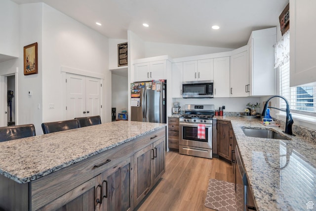 128 E 840 N, Santaquin, UT 84655 - kitchen featuring appliances with stainless steel finishes, vaulted ceiling, white cabinetry, light wood-type flooring, and a center island