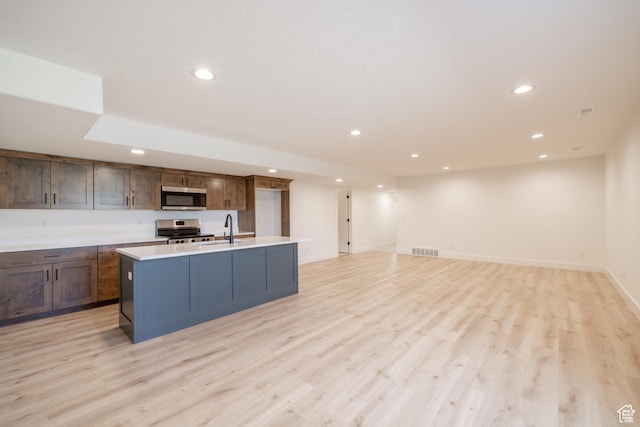335 E Ventura Blvd, Stansbury Park, UT 84074 - kitchen with appliances with stainless steel finishes, recessed lighting, light wood-type flooring, light countertops, and a kitchen island with sink